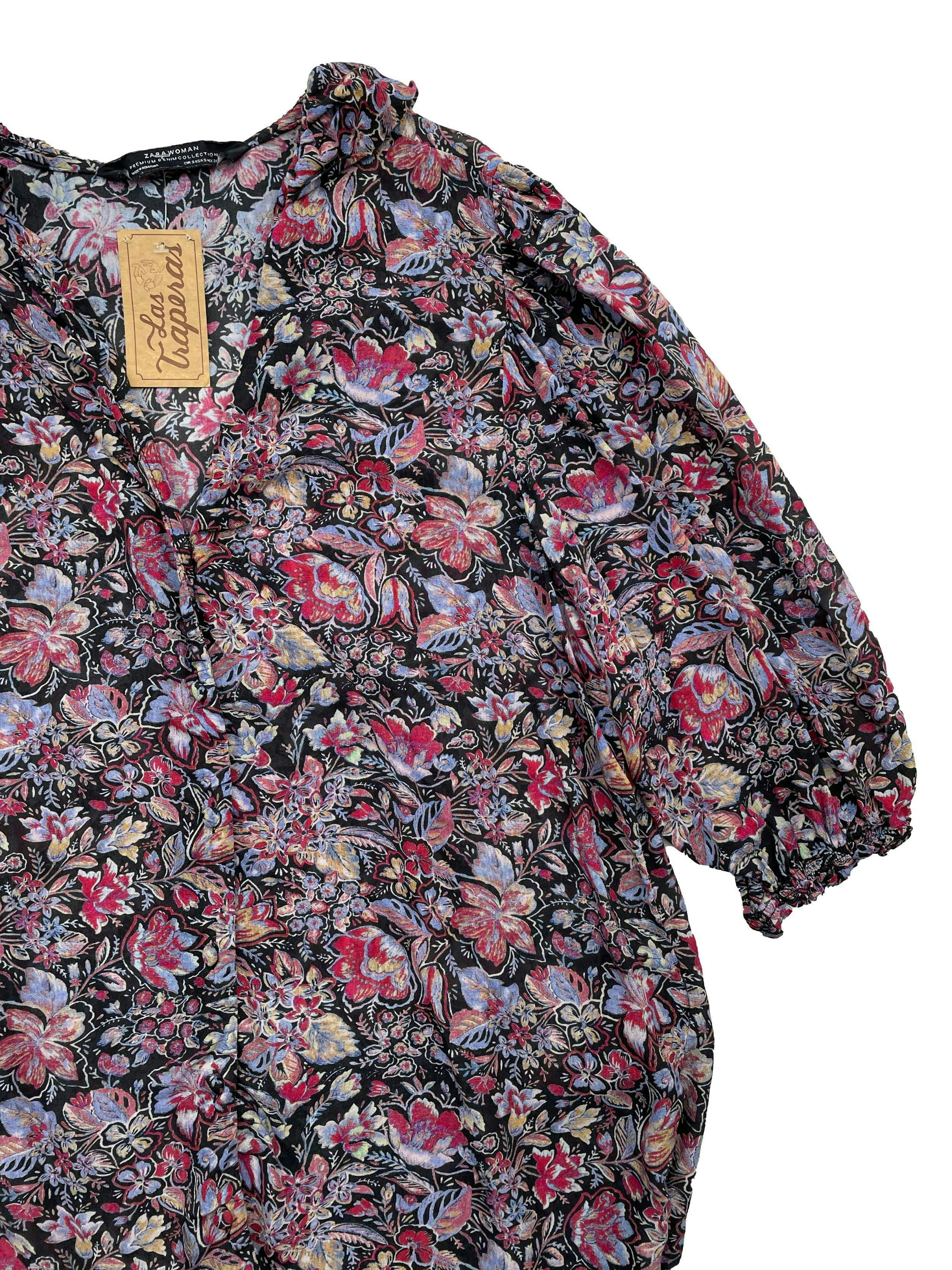 Blusa Zara de gasa negra con flores en tonos morados, volante en cuello, botones delanteros y mangas con volumen y elástico. Busto 100cm Largo 58cm