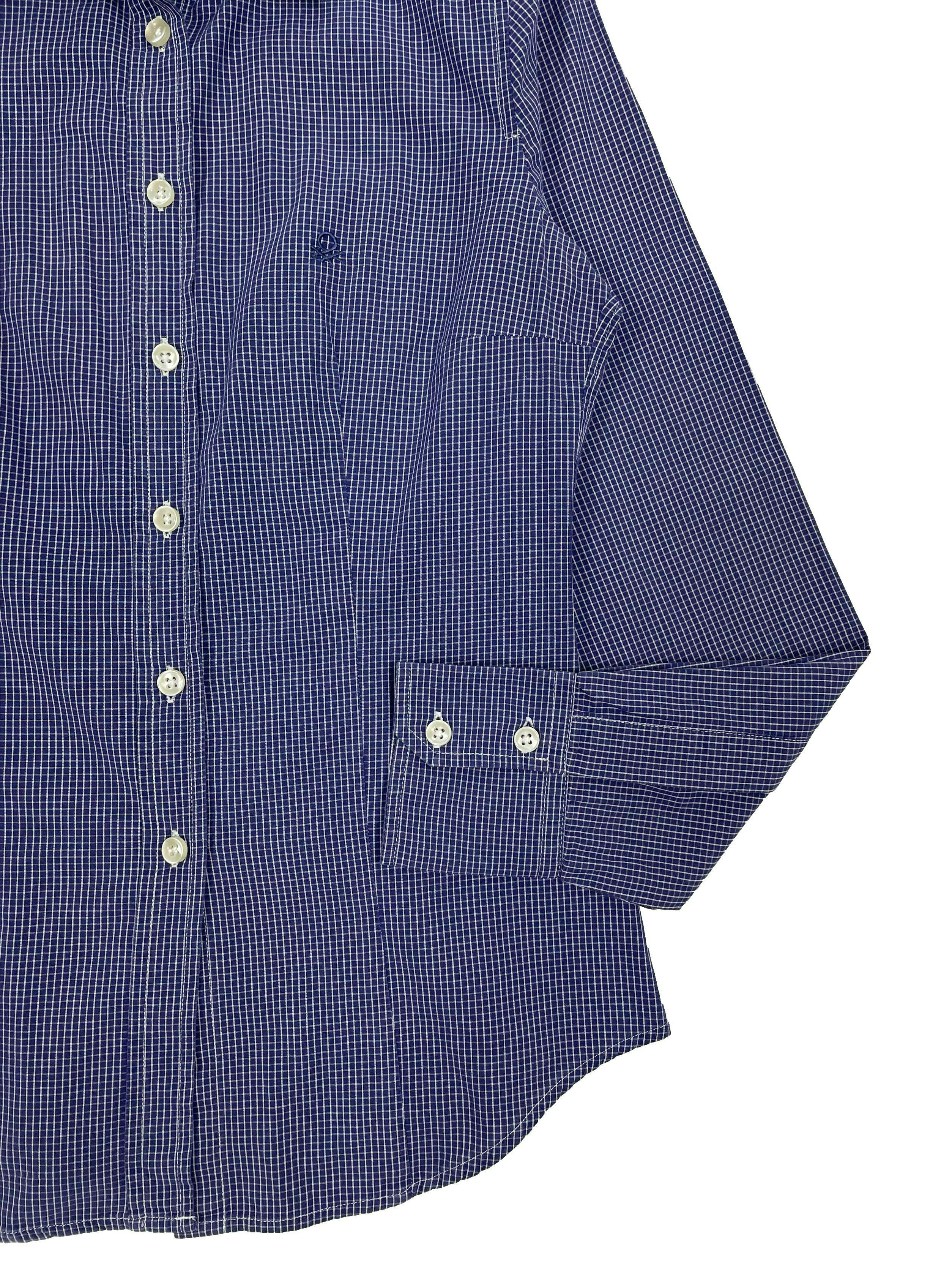 Blusa Benetton a cuadros azul y blanco, corte recto con pinzas en busto, cuello solapa y botones perlados. Busto 86cm, Largo 52cm.