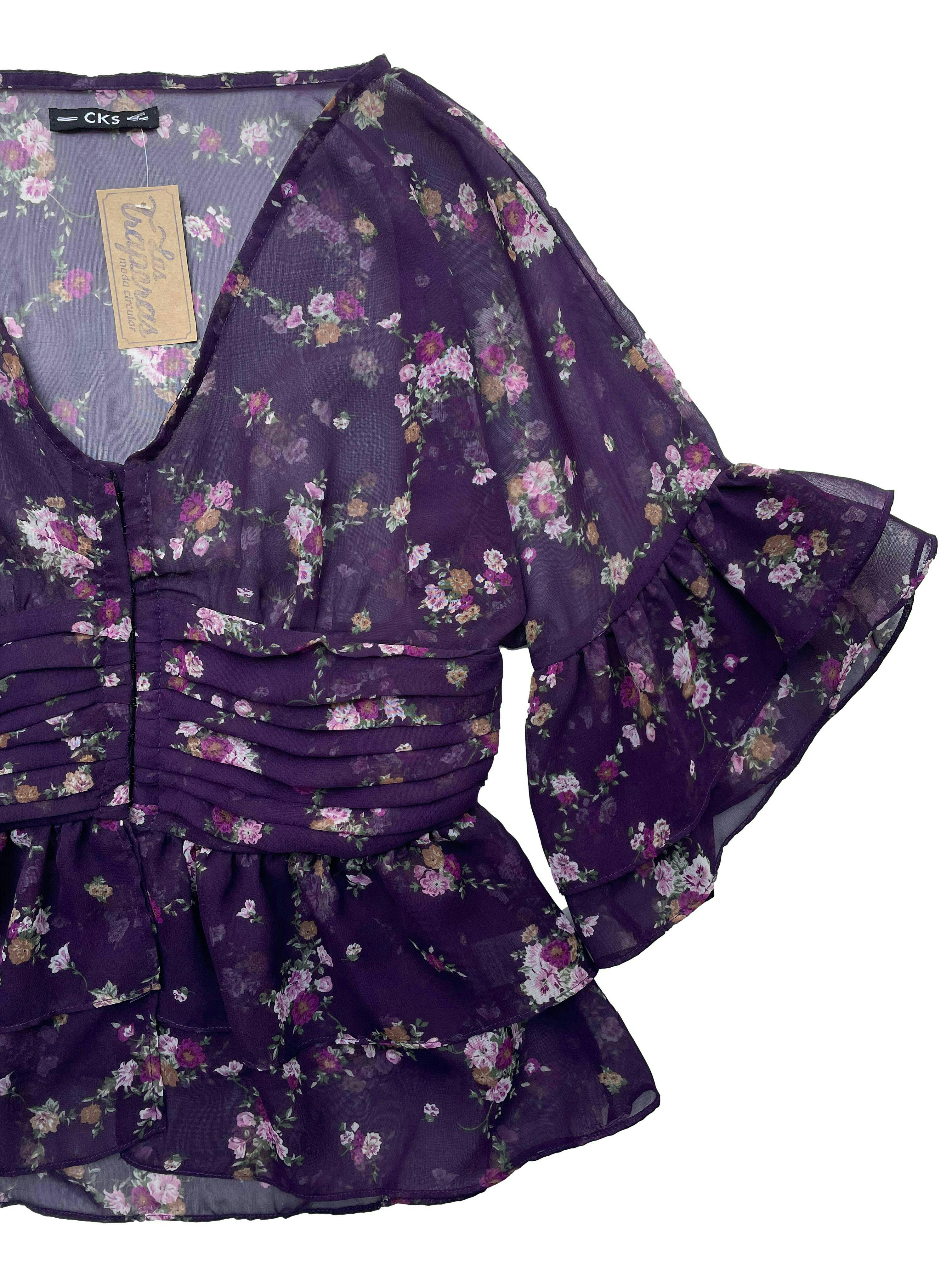 Blusa morada de gasa con estampado floral, escote en V, abertura mediante corchetes, volantes y drapeados. Busto 90cm, Largo 57cm.