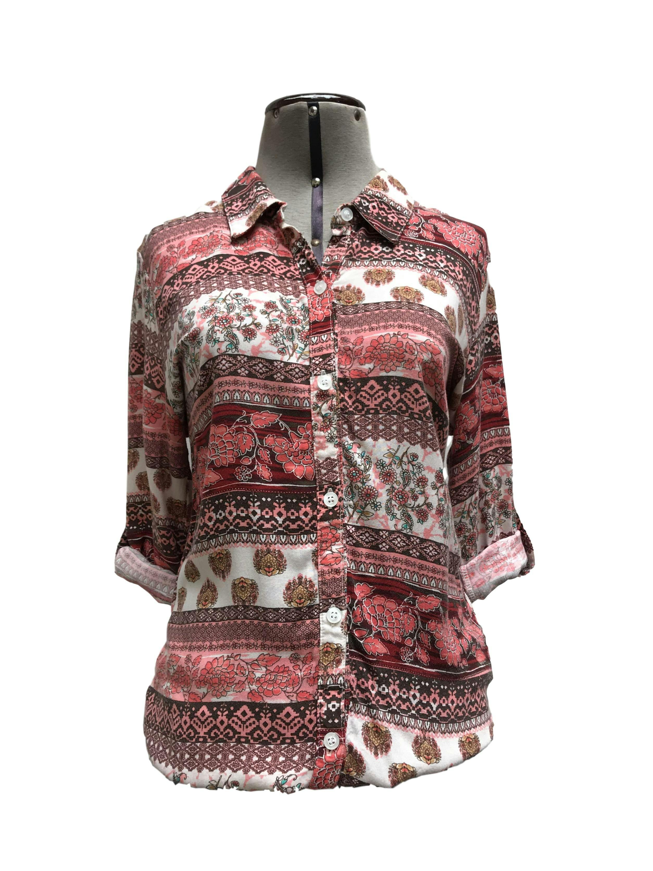 Blusa con estampado tribal en tonos coral, marrón y blanco, cuello camisero, fila de botones y elástico en las basta, manga regulable con botón
Talla S (puede ser M chico)