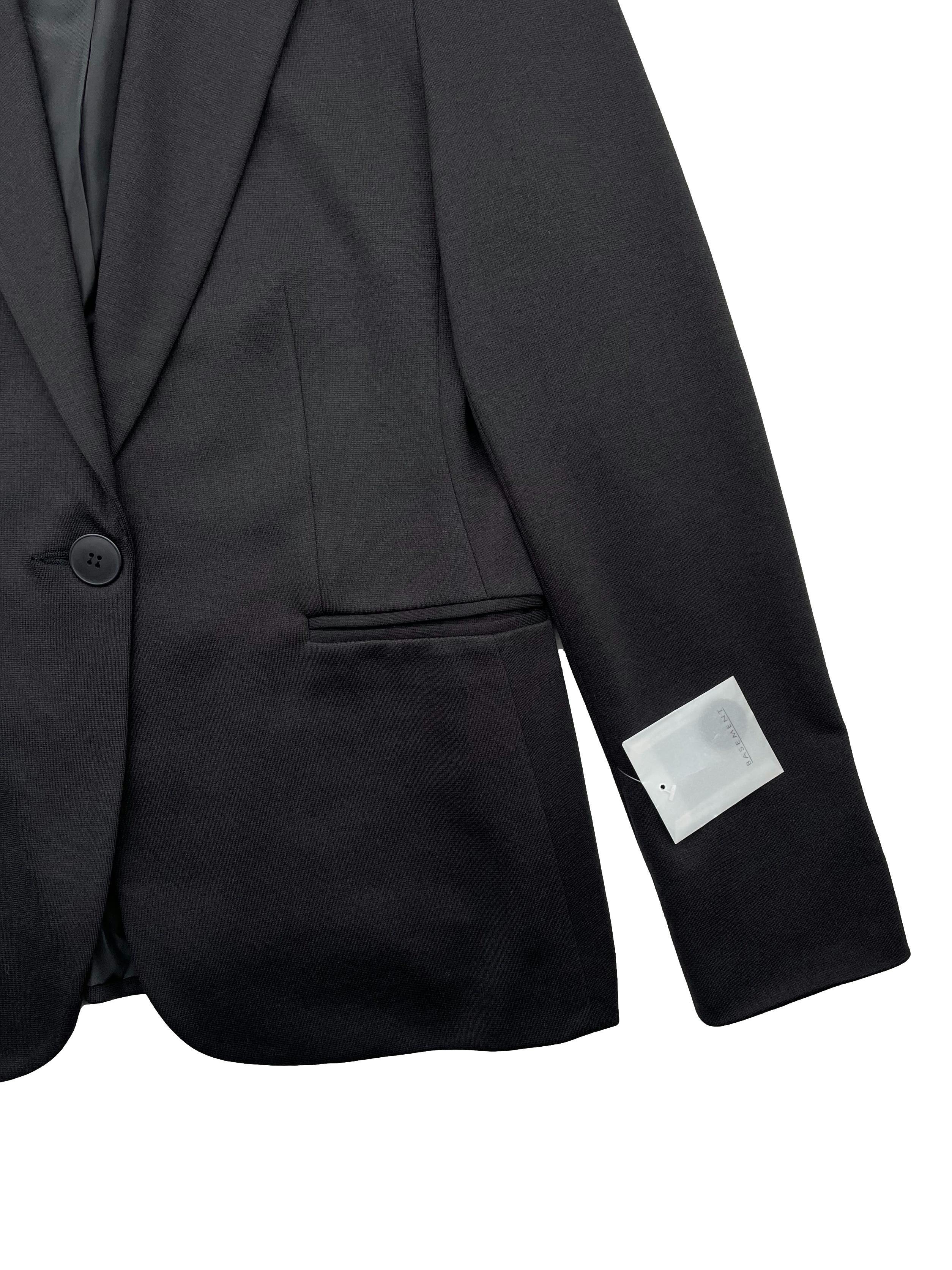 Blazer Basement negro, forrado, con hombreras, falsos bolsillos, botón frontal con uno de repuesto. Talla 40 en etiqueta. Busto 92cm, Largo 63cm.