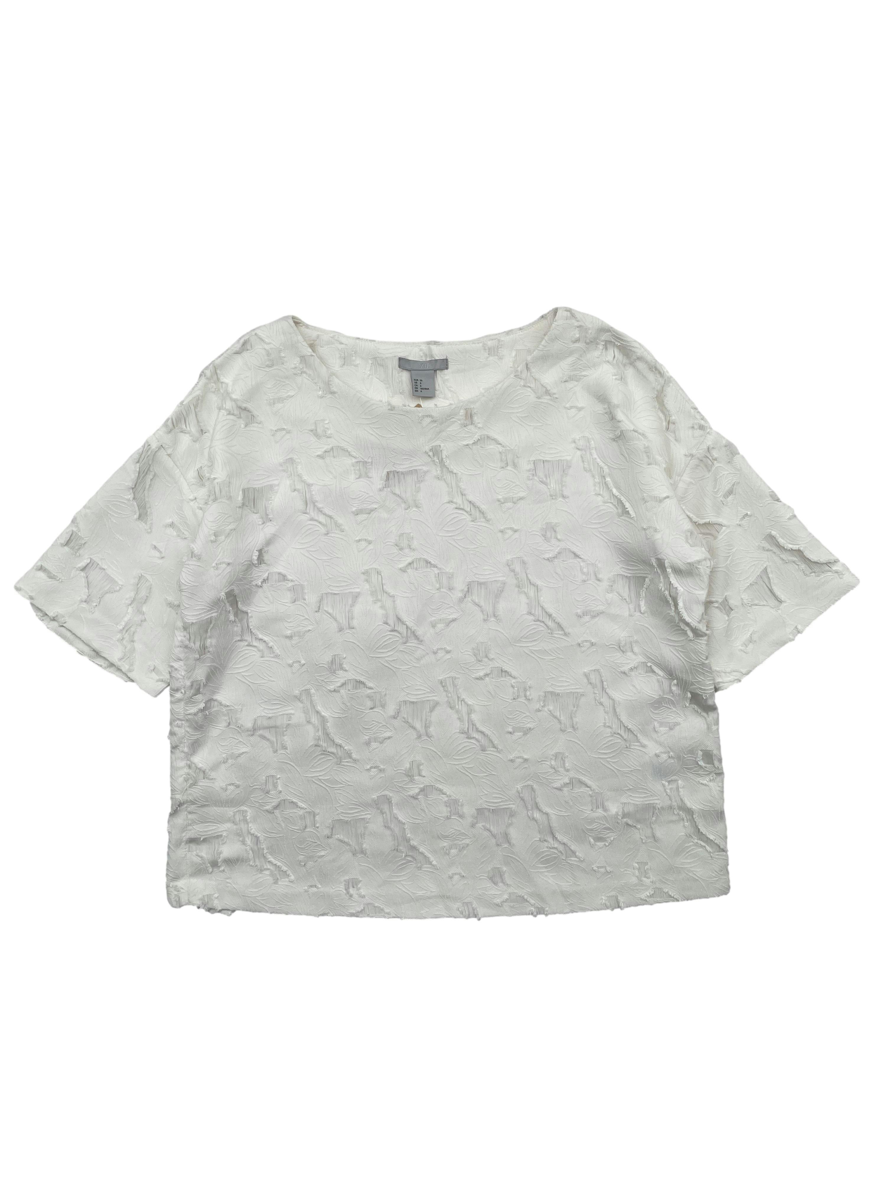 Blusa H&M color perla, tela plana con brocado floral y desflecados, ligera transparencia en los cortes. Busto 108cm, Largo 51cm.