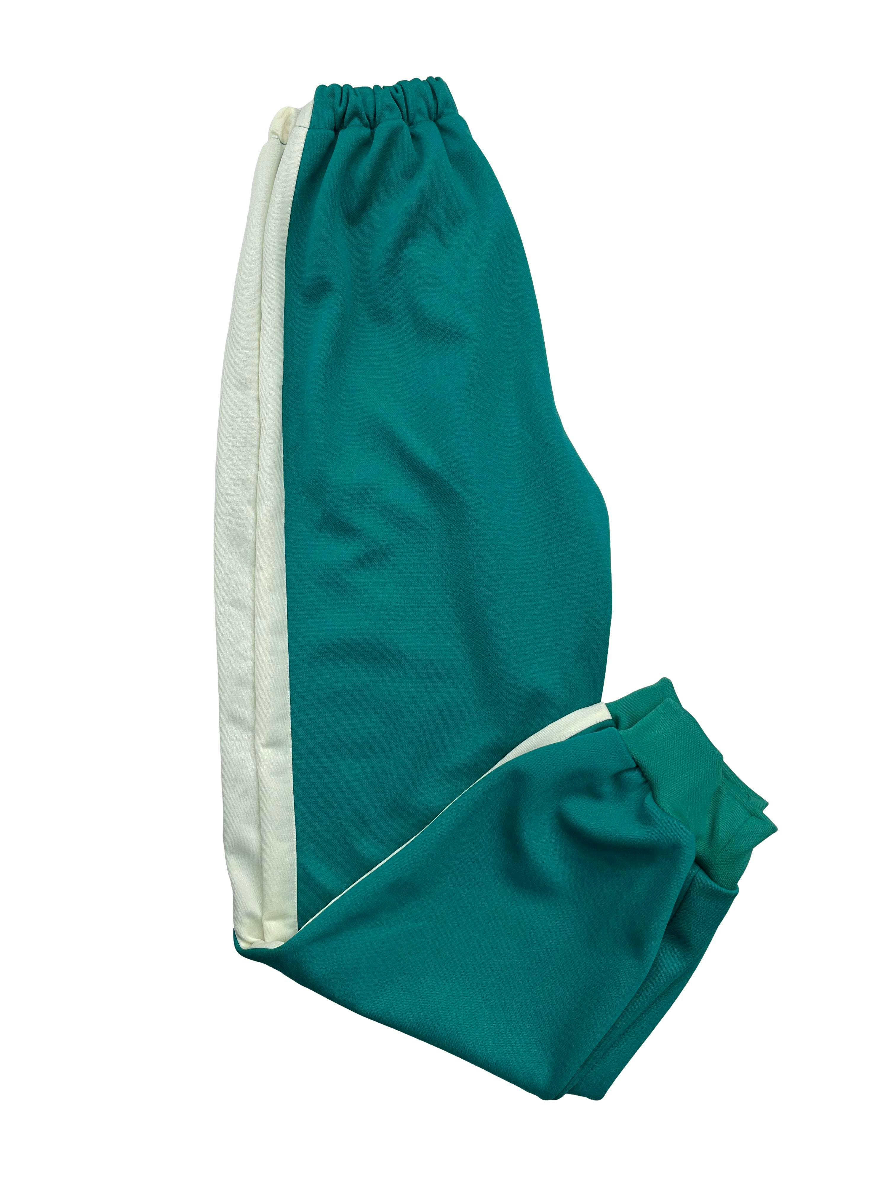 Pantalón buzo verde con líneas laterales beige, bolsillos frontales, pretina y tobillos elásticos. Cintura 52cm sin estirar, Largo 96cm.